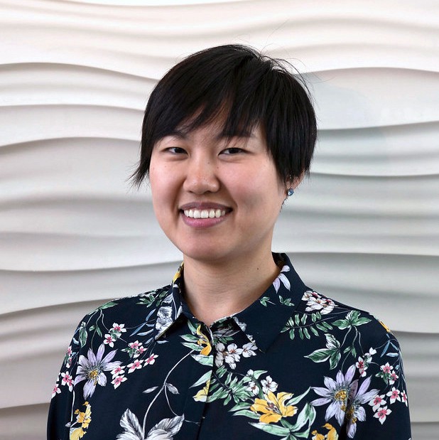 Person with short hair smiling wearing a floral shirt