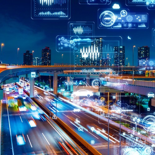 A photo collage of cars on a highway at night with city buildings in the background and various glowing graphs, charts, and symbols int he air and sky around the scene.